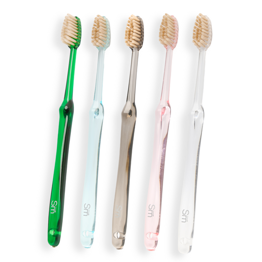 Five toothbrushes in different colors on a white background