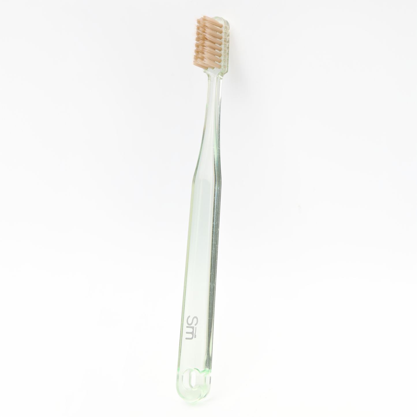Green plastic toothbrush with brown bristles on a white background