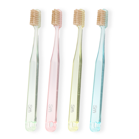Four pastel-colored toothbrushes on a white background