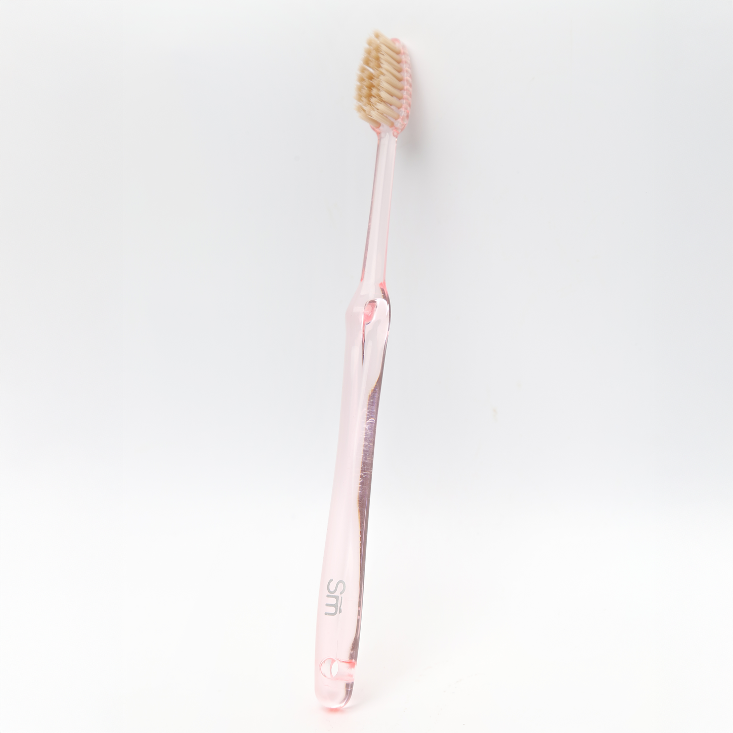 Pink toothbrush with a clear handle on a white background