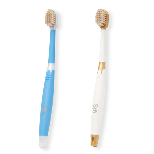 Two toothbrushes, one blue and white, the other white with gold accents, on a white background.