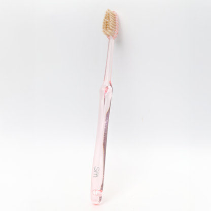 Pink toothbrush with a clear handle on a white background