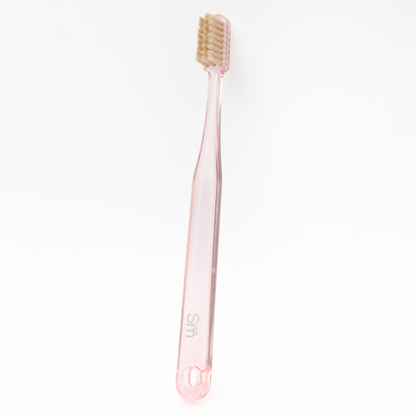 Pink toothbrush with beige bristles on a white background