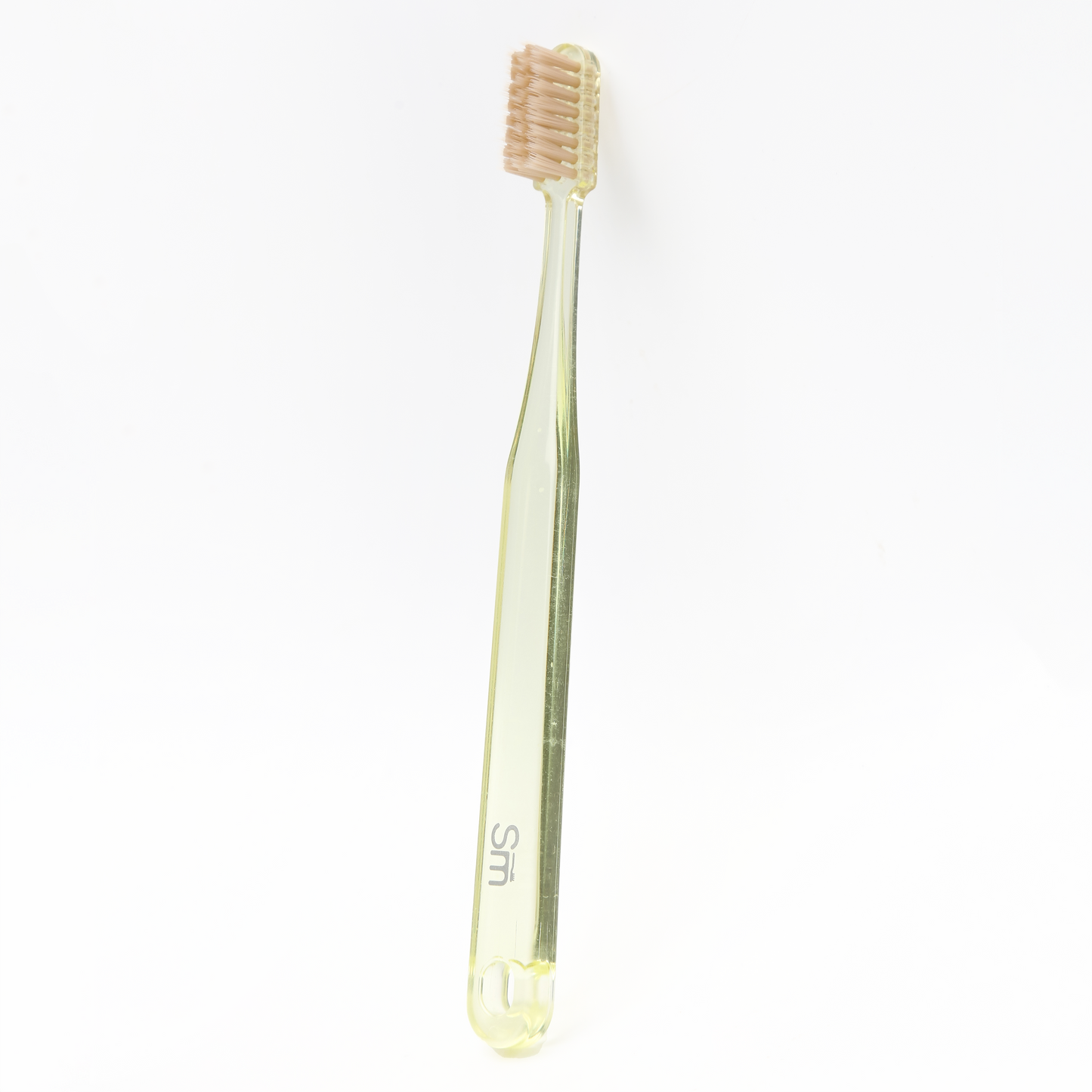 Yellow plastic toothbrush with brown bristles on a white background